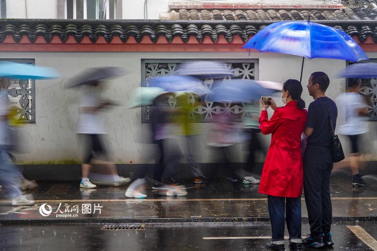 6月7日，在浙江省2023年普通高校招生考試鎮(zhèn)海中學(xué)考點，家長冒雨目送子女進入考場。人民網(wǎng) 章勇濤攝