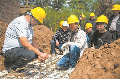 在湖南省常德市安鄉(xiāng)縣一建筑工地，技師（左一）向工人們講解扎筋技巧。新華社記者 周勉攝